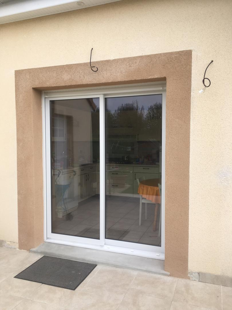 Baie vitrée coulissante PVC blanche sur terrasse donnant sur une cuisine