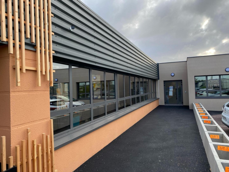 Bandeau de fenêtres à cadres gris anthracite sur façade saumon et bardage métallique