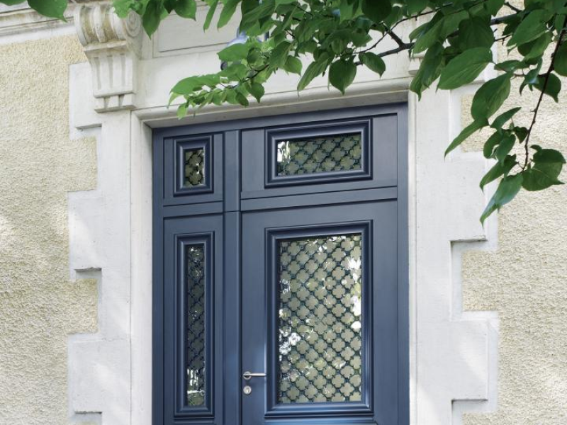 Porte d'entrée anthracite à vitrage décoratif et fixe latéral sur façade pierre