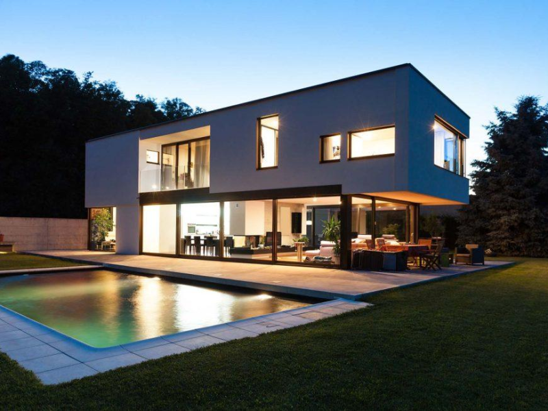 Grande baie vitrée anthracite sur maison blanche moderne, piscine au crépuscule