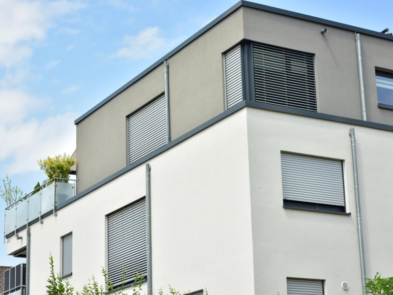 Volets roulants et brise-soleil gris sur façade blanche et grise d'immeuble